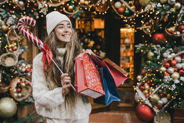 Young beautiful womam enjoying Christmas shopping on a decorated street.