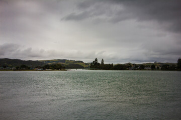 Retro style photo of a breathtakingly serene view of the lake under beautiful, cloudy skies. Raglan, New Zealand. Toned image