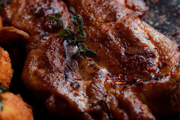 Very close-up turkey steak in caramelized sauce with potato balls on a black plate. Spices - ground pepper, parsley, basil, thyme, white garlic sauce. Detailed texture of fried meat.