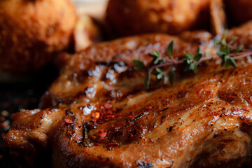 Very close-up turkey steak in caramelized sauce with potato balls on a black plate. Spices - ground pepper, parsley, basil, thyme, white garlic sauce. Detailed texture of fried meat.