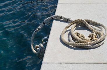 White rope coiled on a stone pier by the sea