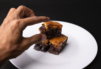 a hand is trying to take the sweet martabak that is on a white plate