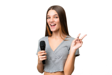 Teenager singer girl picking up a microphone over isolated background smiling and showing victory sign