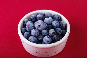 blueberries in a white bowl on a red background