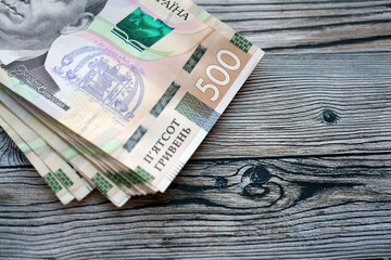 Many five hundred hryvnia money bills lies on wooden background. Ukrainian national currency close...