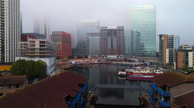 Aerial video over Blackwall Basin waterside and foggy Canary Wharf skyline 
