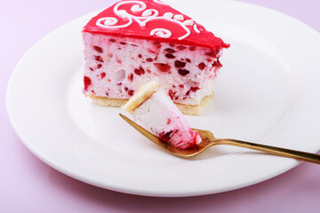 fork breaking delicious mousse cake with pink cream and raspberries on a white background