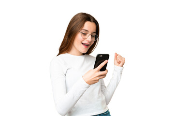 Fototapeta premium Teenager girl over isolated chroma key background with phone in victory position