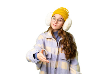 Teenager girl wearing winter muffs over isolated chroma key background shaking hands for closing a good deal