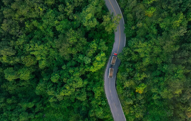 Aerial view of hydrogen energy truck driving on highway road in green forest. Sustainable...