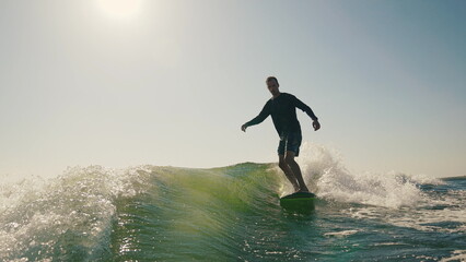 Wakeboarding behind a motor boat on the water surface. An athlete performs tricks while balancing...