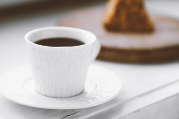 Cup of coffee and a piece of cake on a wooden board