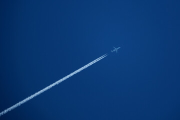 Airplane in the blue sky with white trace of the plane.