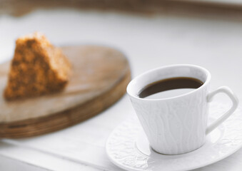 Cup of coffee and a piece of cake on a wooden board