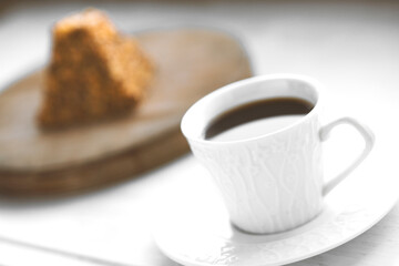 Cup of coffee and a piece of cake on a wooden board