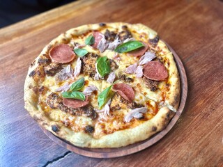 pizza with salami, beef, and cheese on wooden board