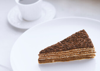Piece of chocolate cake on a wooden plate with a cup of coffee