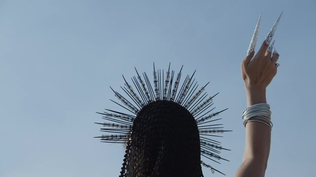 Woman in a tiara with her hand in decorative finger cots raised to the sky
