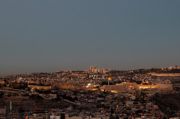 Fototapeta premium Panoramic view of the ancient walls of the Old City of Jerusalem with the golden Dome of the Rock shrine illuminated at twilight.