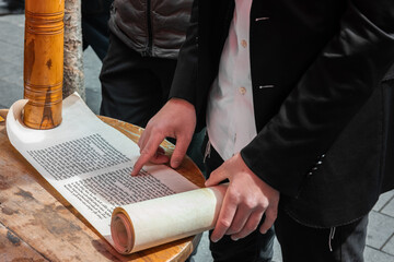 Closeup of a man's hands and fingers as he reads from the Scroll of Esther at an outdoor cafe on...