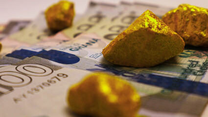Ghanaian cedi notes and Lump of Gold on white background. Raw golden metal ore, galamsey minning...