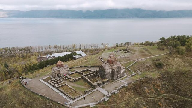 Aerial panoramic view of the Sevanavank Monastery and chapel overlooking famous Sevan lake at cloudy day. Tourist group visit.Travel and tourist destinations of Armenia