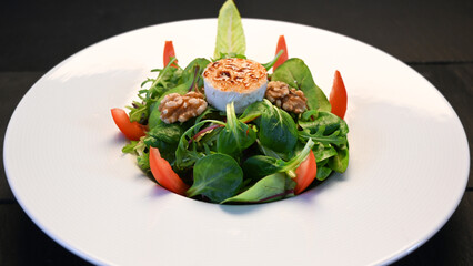 Salad with goat cheese, tomatoes and walnuts on a plate