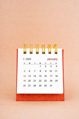 January 2025 white desk calendar on brown background.