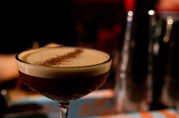 Espresso Martini In a Glass closeup photograph with blurred background in a bar. Espresso martini cocktail, delicious alcohol drink, dessert cocktail. Sophisticated drink, alluring presentation
