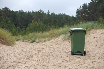 
green garbage can in the sand of the sea beach