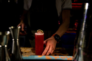 Obraz premium Bartender mixing alcoholic cocktail drink with ice cubes. Bartender hands pouring beverage. Man fingers. Cocktail glass with ice on top. Pouring soda in a cocktail glass. Ring man hands
