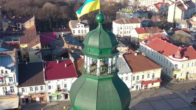 A quadcopter captures a stunning panorama of Drohobych, Ukraine, focusing on the central square where a historic town hall stands proudly. The video highlights the town's charm and rich heritage from