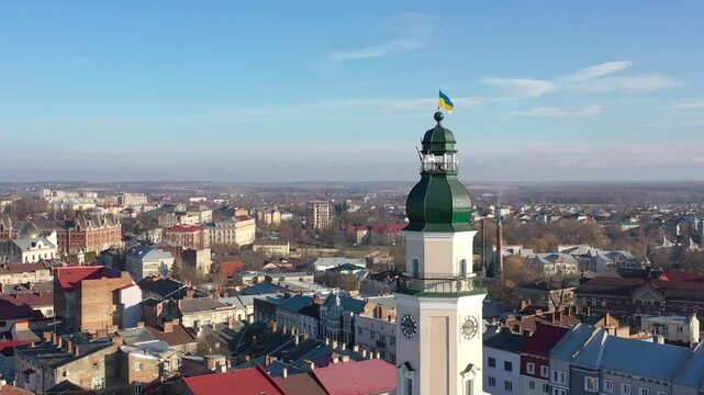A quadcopter captures a stunning panorama of Drohobych, Ukraine, focusing on the central square where a historic town hall stands proudly. The video highlights the town's charm and rich heritage from