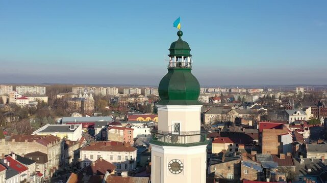 A quadcopter captures a stunning panorama of Drohobych, Ukraine, focusing on the central square where a historic town hall stands proudly. The video highlights the town's charm and rich heritage from
