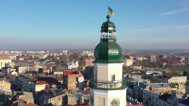 A quadcopter captures a stunning panorama of Drohobych, Ukraine, focusing on the central square where a historic town hall stands proudly. The video highlights the town's charm and rich heritage from