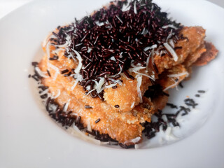 Pisang Bakar Coklat Keju or Grilled Banana Chocolate Cheese serve with chocolate sprinkles and cheddar cheese graters on white plate.