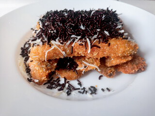 Pisang Bakar Coklat Keju or Grilled Banana Chocolate Cheese serve with chocolate sprinkles and cheddar cheese graters on white plate.