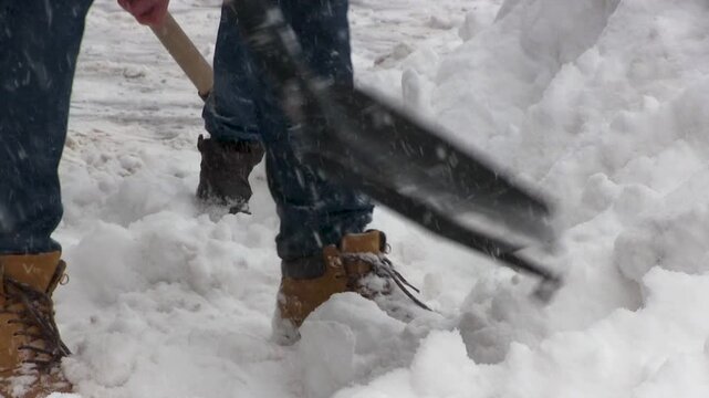 Snow piles cover streets as people work with shovels, making a path for pedestrians. Cold winter day demands endurance and coordinated efforts to tackle heavy snow