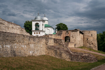 View of the wall of the Izborsk fortress, the Nikolsky Gate and St. Nicholas (Nikolsky) Cathedral (XIV-XVII century) on a sunny summer day, Izborsk, Pskov region, Russia