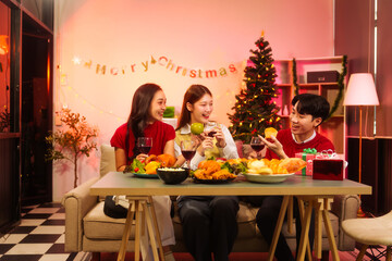 Lively New Year Eve and christmas party Asian friends and colleagues of various ages celebrating together. Champagne, wine, gift boxes, festive decorations create a warm, joyful holiday atmosphere.