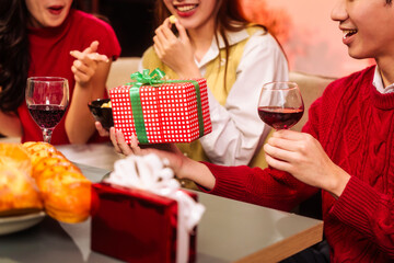 Lively New Year Eve and christmas party Asian friends and colleagues of various ages celebrating together. Champagne, wine, gift boxes, festive decorations create a warm, joyful holiday atmosphere.