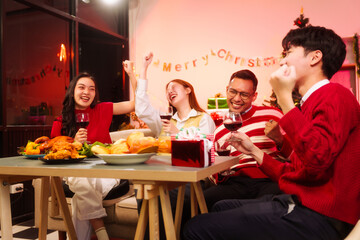 Lively New Year Eve and christmas party Asian friends and colleagues of various ages celebrating together. Champagne, wine, gift boxes, festive decorations create a warm, joyful holiday atmosphere.