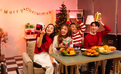 Lively New Year Eve and christmas party Asian friends and colleagues of various ages celebrating together. Champagne, wine, gift boxes, festive decorations create a warm, joyful holiday atmosphere.