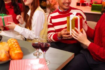 Lively New Year Eve and christmas party Asian friends and colleagues of various ages celebrating together. Champagne, wine, gift boxes, festive decorations create a warm, joyful holiday atmosphere.