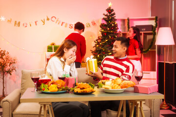 Lively New Year Eve and christmas party Asian friends and colleagues of various ages celebrating together. Champagne, wine, gift boxes, festive decorations create a warm, joyful holiday atmosphere.