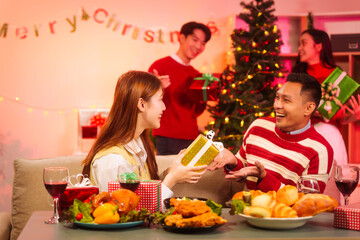 Lively New Year Eve and christmas party Asian friends and colleagues of various ages celebrating together. Champagne, wine, gift boxes, festive decorations create a warm, joyful holiday atmosphere.