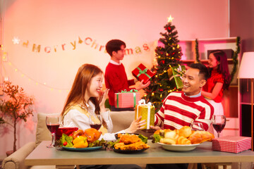 Lively New Year Eve and christmas party Asian friends and colleagues of various ages celebrating together. Champagne, wine, gift boxes, festive decorations create a warm, joyful holiday atmosphere.