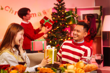Lively New Year Eve and christmas party Asian friends and colleagues of various ages celebrating together. Champagne, wine, gift boxes, festive decorations create a warm, joyful holiday atmosphere.