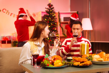 Lively New Year Eve and christmas party Asian friends and colleagues of various ages celebrating together. Champagne, wine, gift boxes, festive decorations create a warm, joyful holiday atmosphere.