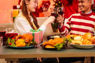 Lively New Year Eve and christmas party Asian friends and colleagues of various ages celebrating together. Champagne, wine, gift boxes, festive decorations create a warm, joyful holiday atmosphere.